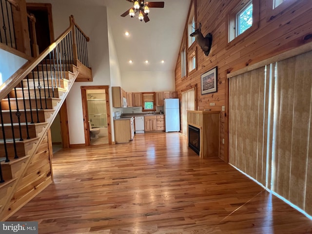 1000 Cardinal View Rd, Paw Paw, WV 25434 - unfurnished living room with high vaulted ceiling, wood walls, a ceiling fan, stairway, and a glass covered fireplace