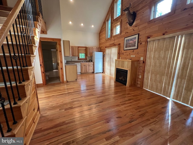 1000 Cardinal View Rd, Paw Paw, WV 25434 - unfurnished living room featuring high vaulted ceiling, light wood-style floors, wood walls, a fireplace, and stairs