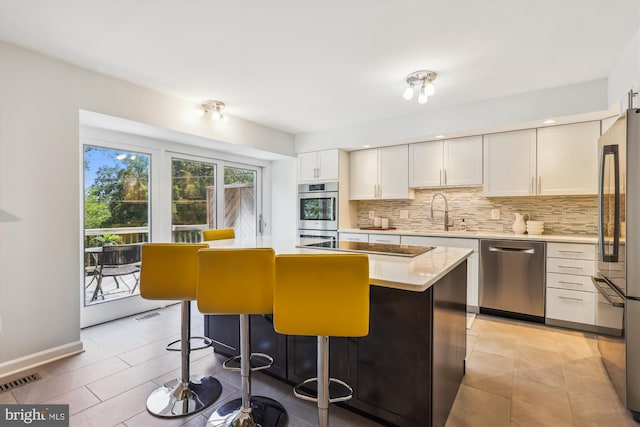4410 S Pershing Ct, Arlington, VA 22204 - kitchen featuring stainless steel appliances, a sink, backsplash, white cabinets, and a center island