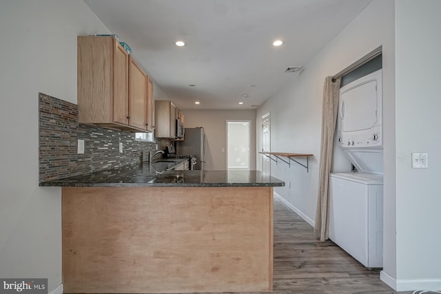 318 12th St, Hammonton, NJ 08037 - kitchen featuring stacked washer / drying machine, wood finished floors, baseboards, dark stone counters, and decorative backsplash