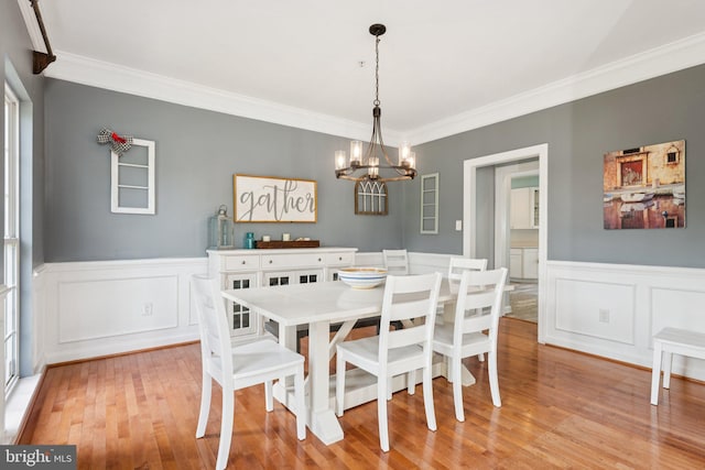14520 Fairdale Rd, Silver Spring, MD 20905 - dining space with a chandelier, crown molding, a wainscoted wall, light wood-style flooring, and a decorative wall