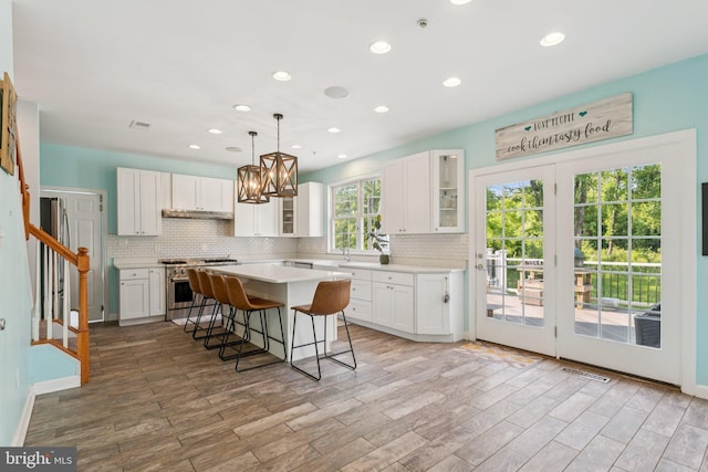 14520 Fairdale Rd, Silver Spring, MD 20905 - kitchen with high end range, a breakfast bar area, backsplash, a center island, and white cabinets