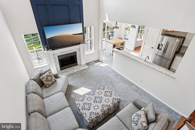 1112 Cornwallis Way, Collegeville, PA 19426 - carpeted living area featuring plenty of natural light, a towering ceiling, a high end fireplace, and baseboards