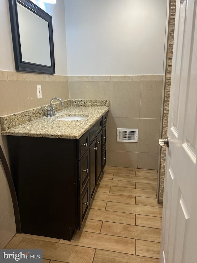 5603 Florence Ave, Philadelphia, PA 19143 - bathroom featuring tile walls, wood finish floors, vanity, and a wainscoted wall