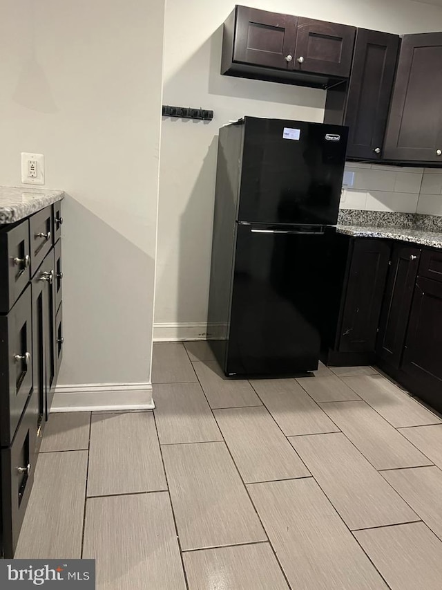 5603 Florence Ave, Philadelphia, PA 19143 - kitchen featuring freestanding refrigerator, light stone countertops, wood tiled floors, decorative backsplash, and baseboards
