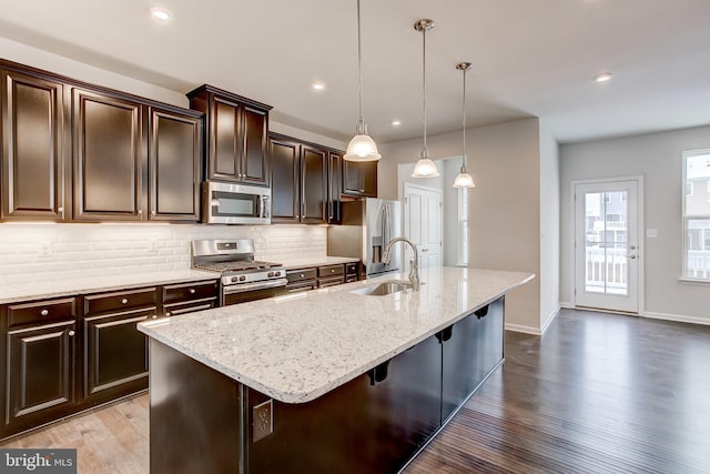 9608 Julia Ln, Owings Mills, MD 21117 - kitchen featuring stainless steel appliances, a sink, wood finished floors, an island with sink, and light stone counters