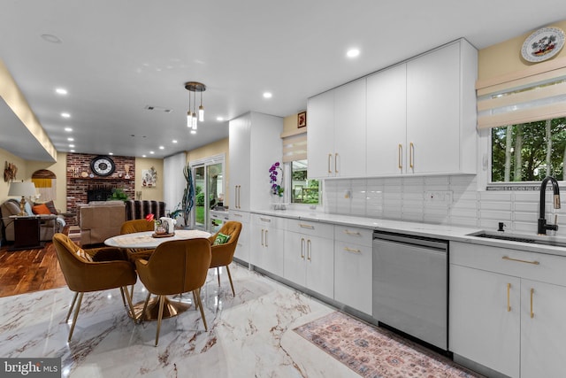 95 Meadowfield Dr, Southampton, PA 18966 - kitchen featuring stainless steel dishwasher, a sink, decorative backsplash, a brick fireplace, and white cabinetry