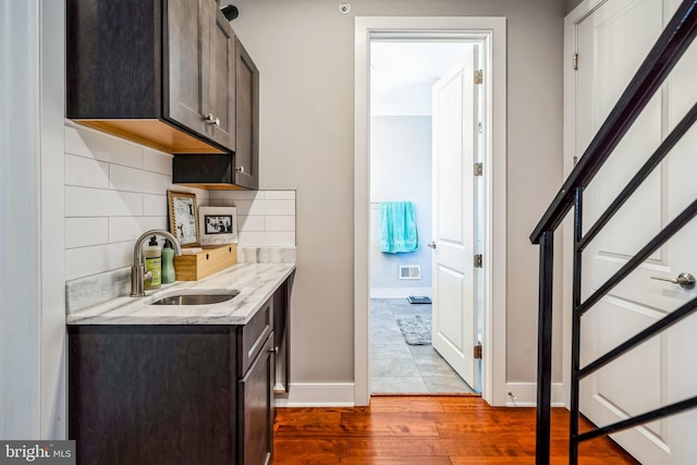 1603 S 6th St, Philadelphia, PA 19148 - kitchen with wood finished floors, decorative backsplash, dark brown cabinetry, and light stone counters