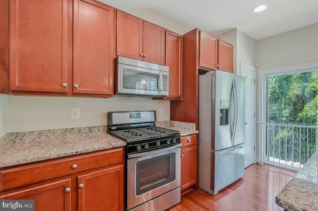 12310 Sandstone St, Waldorf, MD 20601 - kitchen featuring appliances with stainless steel finishes, light wood-style floors, light stone counters, recessed lighting, and brown cabinetry