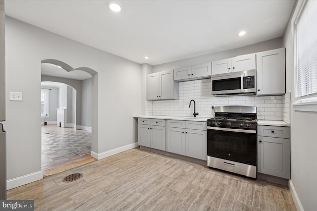 2434 N 26th St, Philadelphia, PA 19132 - kitchen featuring appliances with stainless steel finishes, gray cabinets, light countertops, decorative backsplash, and recessed lighting