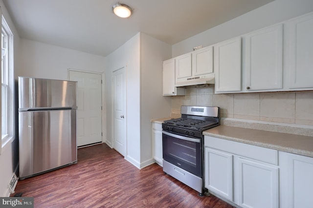 753 N 12th St, Reading, PA 19604 - kitchen featuring appliances with stainless steel finishes, under cabinet range hood, tasteful backsplash, white cabinets, and dark wood-style flooring