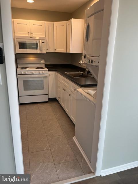 8 Florence Tollgate Pl, Florence, NJ 08518 - kitchen featuring white appliances, stacked washing machine and dryer, white cabinets, dark countertops, and recessed lighting