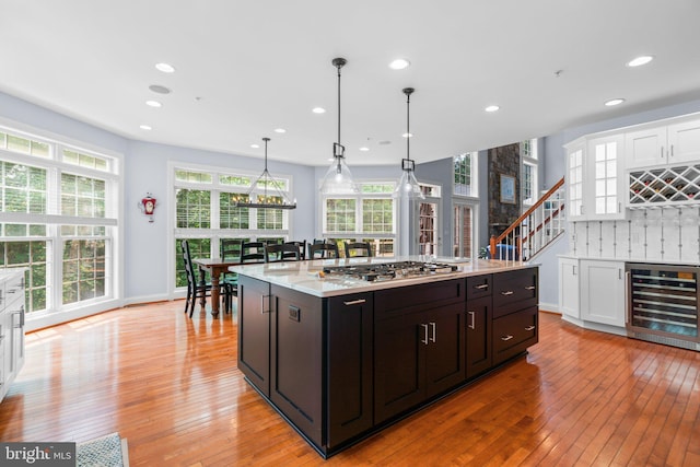 505 Sherwood Mills Ct, Sandy Spring, MD 20860 - kitchen with beverage cooler, light wood-style flooring, white cabinetry, stainless steel gas stovetop, and recessed lighting