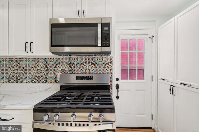2254 12th St NW, Washington, DC 20009 - kitchen with stainless steel appliances, white cabinets, decorative backsplash, and light stone countertops
