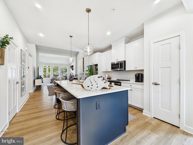 11020 Augusta Ln Unit 3, Berlin, MD 21811 - kitchen with stainless steel microwave, a breakfast bar area, electric stove, white cabinets, and light wood finished floors