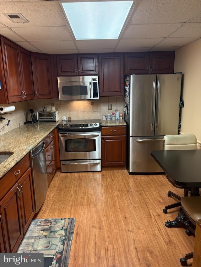 3108 Centennial Unit 310, Warminster, PA 18974 - kitchen with appliances with stainless steel finishes, a drop ceiling, light wood-style floors, decorative backsplash, and light stone countertops