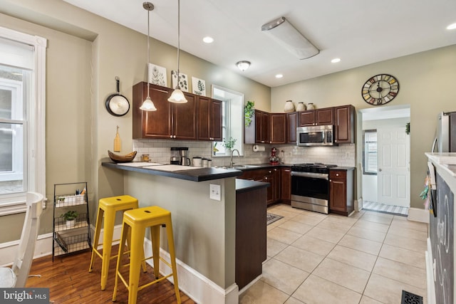 152 W Sharpnack St, Philadelphia, PA 19119 - kitchen featuring stainless steel appliances, a breakfast bar area, a peninsula, backsplash, and a sink