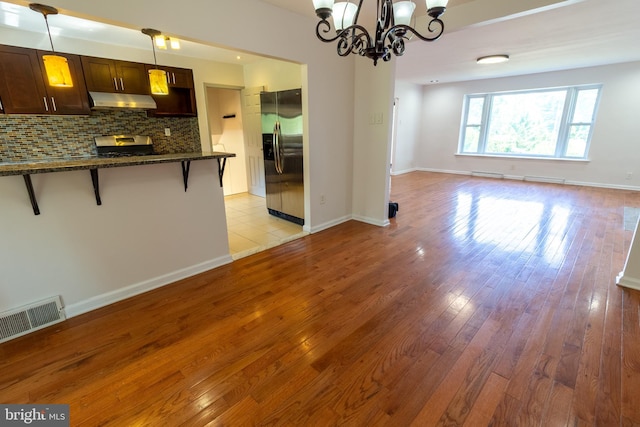 1545 Shoemaker Rd, Abington, PA 19001 - kitchen with stainless steel fridge, under cabinet range hood, a breakfast bar area, dark brown cabinets, and decorative backsplash