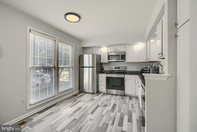 608 Budleigh Cir, Lutherville Timonium, MD 21093 - kitchen with stainless steel appliances, white cabinets, light wood-style flooring, and dark countertops