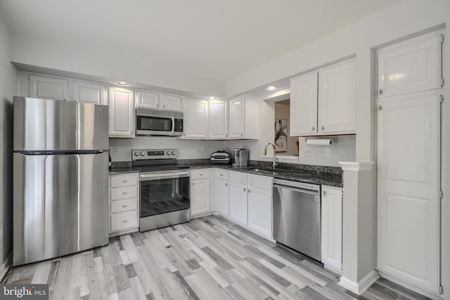 608 Budleigh Cir, Lutherville Timonium, MD 21093 - kitchen featuring stainless steel appliances, white cabinetry, light wood-style floors, recessed lighting, and dark stone countertops