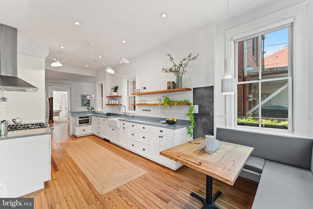 111 8th St SE, Washington, DC 20003 - kitchen featuring wall chimney range hood, open shelves, white cabinetry, appliances with stainless steel finishes, and a sink