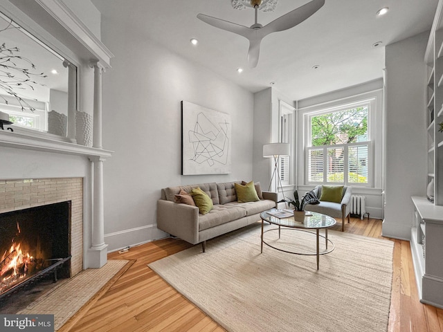 111 8th St SE, Washington, DC 20003 - living area featuring a brick fireplace, radiator, a ceiling fan, wood finished floors, and baseboards