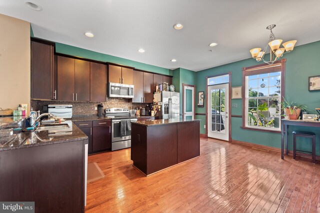 4500 Fait Ave, Baltimore, MD 21224 - kitchen featuring appliances with stainless steel finishes, a center island, a chandelier, backsplash, and dark stone countertops