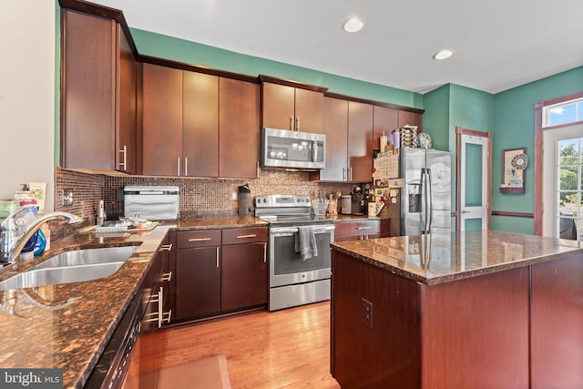 4500 Fait Ave, Baltimore, MD 21224 - kitchen featuring appliances with stainless steel finishes, light wood-style floors, tasteful backsplash, dark stone countertops, and a kitchen island