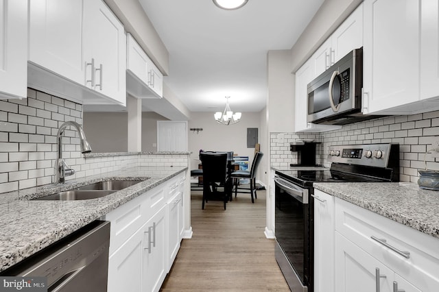 1601 Carriage House Ter Unit D, Silver Spring, MD 20904 - kitchen with appliances with stainless steel finishes, a sink, white cabinets, decorative backsplash, and a chandelier