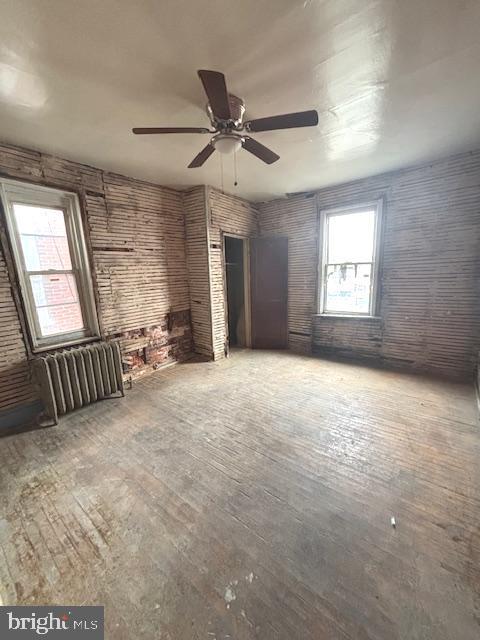 5328 Willows Ave, Philadelphia, PA 19143 - unfurnished living room with ceiling fan, hardwood / wood-style floors, radiator heating unit, and brick wall