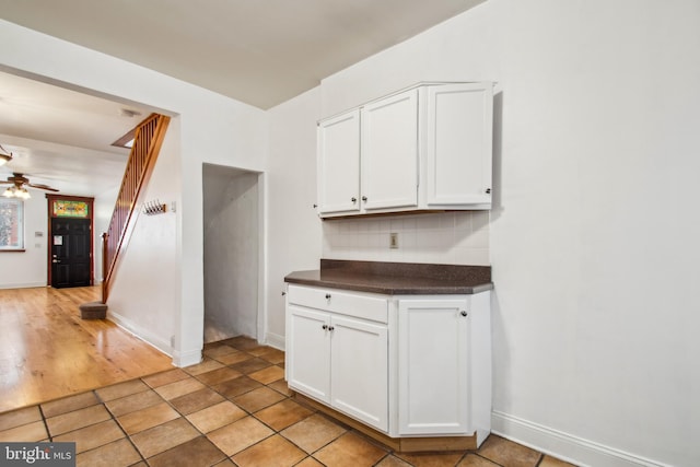 3305 Fleet St, Baltimore, MD 21224 - kitchen with dark countertops, decorative backsplash, white cabinets, a ceiling fan, and baseboards