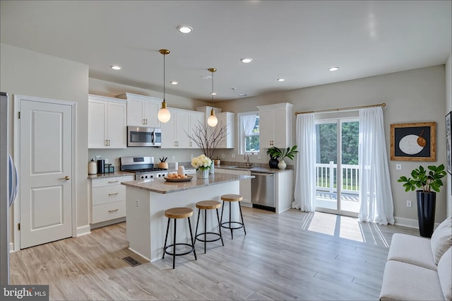 35141 Wright Way, Millsboro, DE 19966 - kitchen featuring appliances with stainless steel finishes, a sink, a center island, light wood-style floors, and white cabinetry