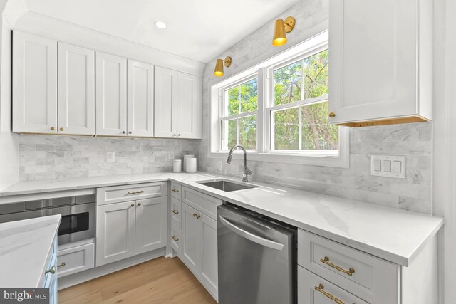 2402 E Randolph Ave, Alexandria, VA 22301 - kitchen with stainless steel dishwasher, a sink, backsplash, light stone countertops, and white cabinetry