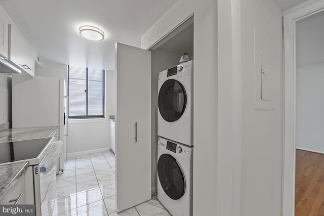 1140 23rd St NW Unit 903, Washington, DC 20037 - laundry area with stacked washer and clothes dryer, light marble finish flooring, and baseboards