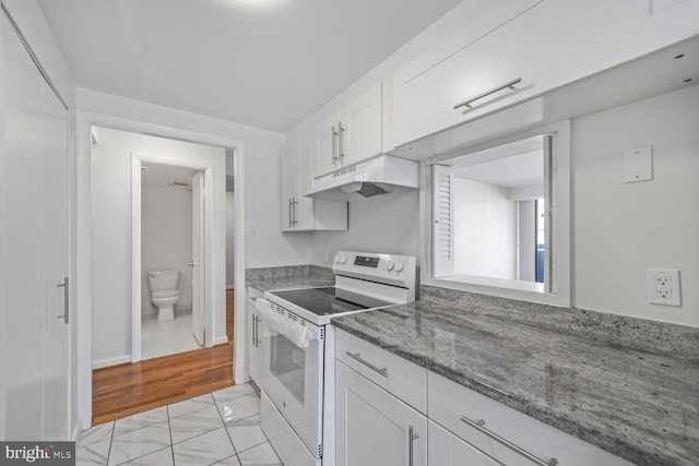 1140 23rd St NW Unit 903, Washington, DC 20037 - kitchen with electric stove, under cabinet range hood, white cabinets, light stone counters, and light marble finish flooring