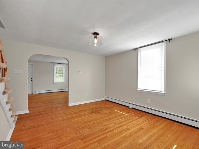 41 W George St, York, PA 17408 - empty room with arched walkways, a baseboard radiator, light wood-style flooring, and stairs