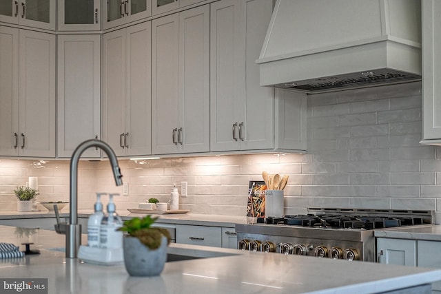 547 Webb Rd # Ad, Chadds Ford, PA 19317 - kitchen with wall chimney exhaust hood, light countertops, backsplash, glass insert cabinets, and stove