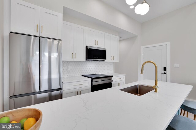 4019 9th St NE Unit 3, Washington, DC 20017 - kitchen featuring stainless steel appliances, a sink, white cabinets, decorative backsplash, and a breakfast bar