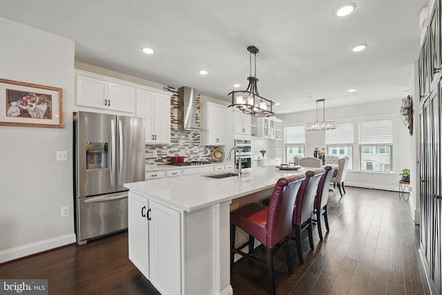 2069 Alder Ln, Dumfries, VA 22026 - kitchen featuring stainless steel appliances, wall chimney exhaust hood, a sink, a center island with sink, and white cabinets
