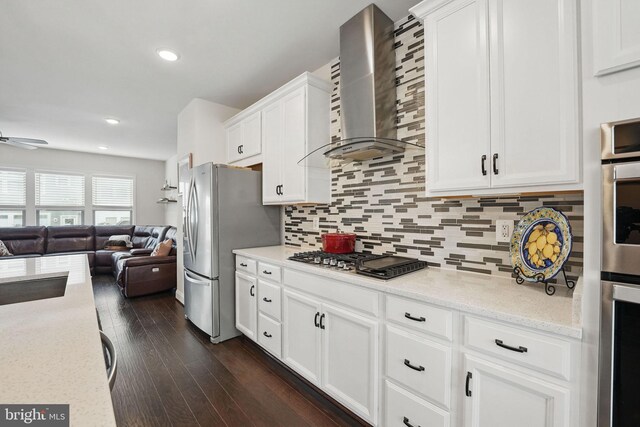 2069 Alder Ln, Dumfries, VA 22026 - kitchen featuring appliances with stainless steel finishes, wall chimney range hood, open floor plan, white cabinetry, and backsplash