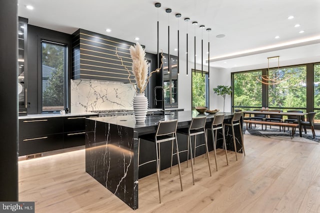 1519 Spring Vale Ave, Mclean, VA 22101 - kitchen featuring modern cabinets, dark cabinets, backsplash, a kitchen island with sink, and light wood-style floors