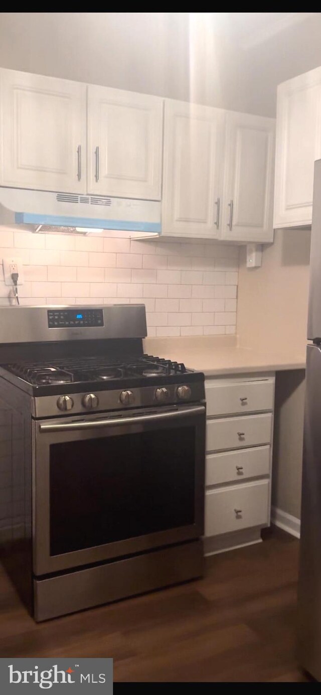 4019 N Marshall St, Philadelphia, PA 19140 - kitchen featuring appliances with stainless steel finishes, white cabinetry, under cabinet range hood, dark wood-style flooring, and tasteful backsplash