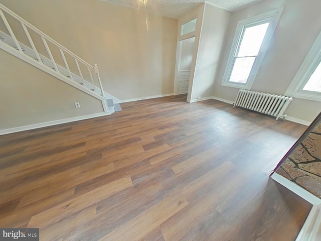 4019 N Marshall St, Philadelphia, PA 19140 - unfurnished living room featuring radiator heating unit, wood finished floors, and stairway