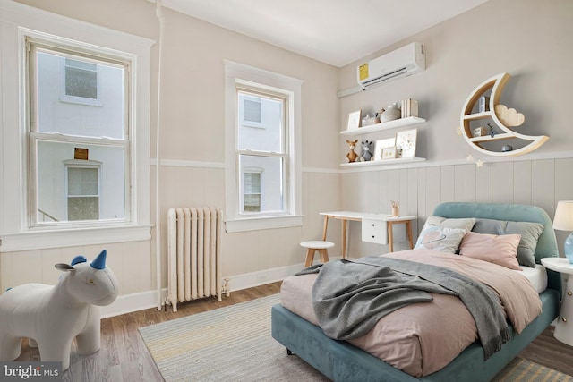 1003 Walnut Ave, Baltimore, MD 21229 - bedroom with radiator heating unit, a wall unit AC, a wainscoted wall, wood finished floors, and baseboards