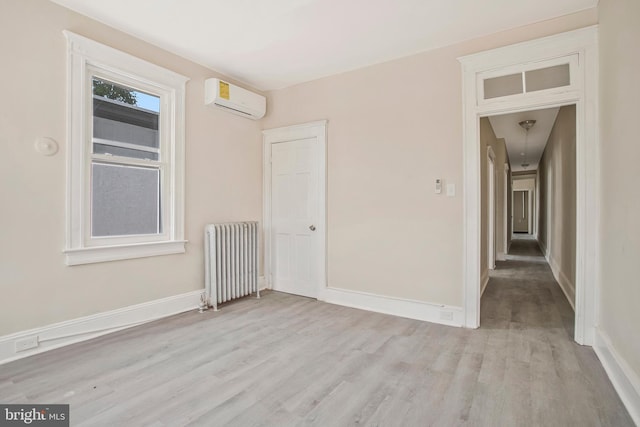1003 Walnut Ave, Baltimore, MD 21229 - unfurnished room featuring radiator heating unit, light wood-type flooring, a wall mounted AC, and baseboards