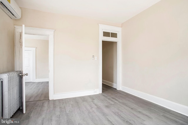 1003 Walnut Ave, Baltimore, MD 21229 - spare room with an AC wall unit, wood finished floors, radiator heating unit, and baseboards