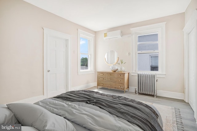 1003 Walnut Ave, Baltimore, MD 21229 - bedroom with radiator heating unit, a wall mounted AC, wood finished floors, and baseboards