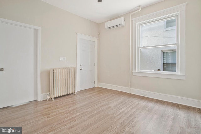 1003 Walnut Ave, Baltimore, MD 21229 - spare room featuring radiator, a wall mounted air conditioner, light wood-style flooring, and baseboards