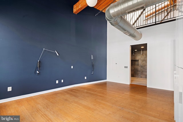 1147 N 4th St Unit 6F, Philadelphia, PA 19123 - unfurnished room with a high ceiling, baseboards, wood finished floors, and beam ceiling