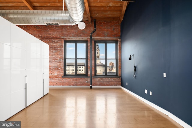 1147 N 4th St Unit 6F, Philadelphia, PA 19123 - empty room with wood finished floors, baseboards, brick wall, and beamed ceiling